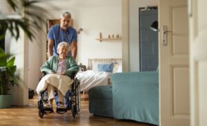 Nurse pushing wheelchair of elderly person into room