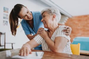 Caregiver and elderly resident in assisted living community embracing each other 