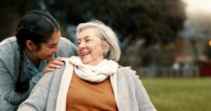 Caregiver laughing with happy assisted living resident outdoors